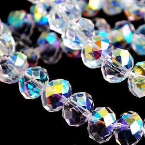 Op de afbeelding: Een streng iriserende, heldere glazen kralen. De kralen zijn gefacetteerd en hebben een regenboogkleurige glans.