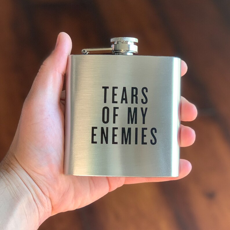 May include: A silver flask with the text "Tears of My Enemies" printed in black.