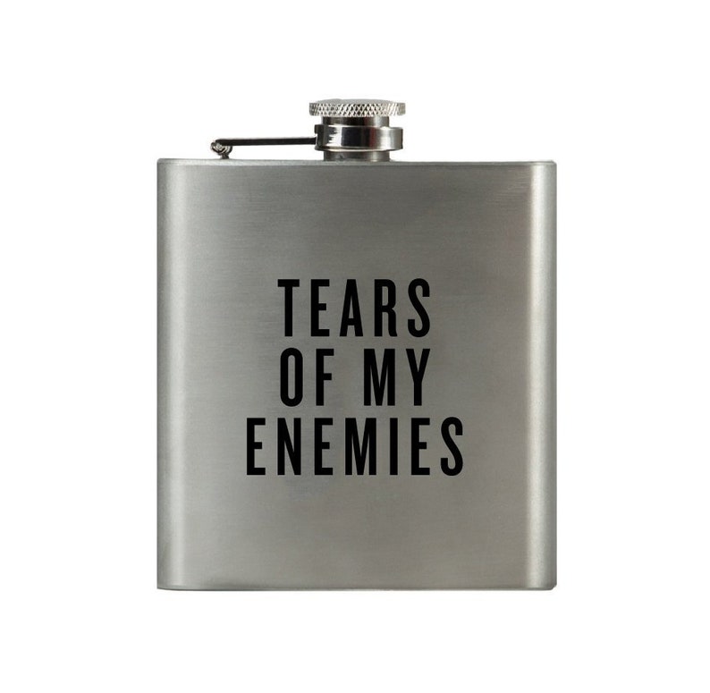 May include: A silver flask with a black inscription that reads "Tears of my Enemies".