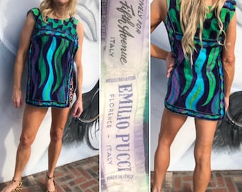 May include: A blue, green, and purple patterned mini dress with a sleeveless design. The dress has a label that reads "Emilio Pucci, Florence - Italy, Exclusively for Saks Fifth Avenue, Made in Italy".