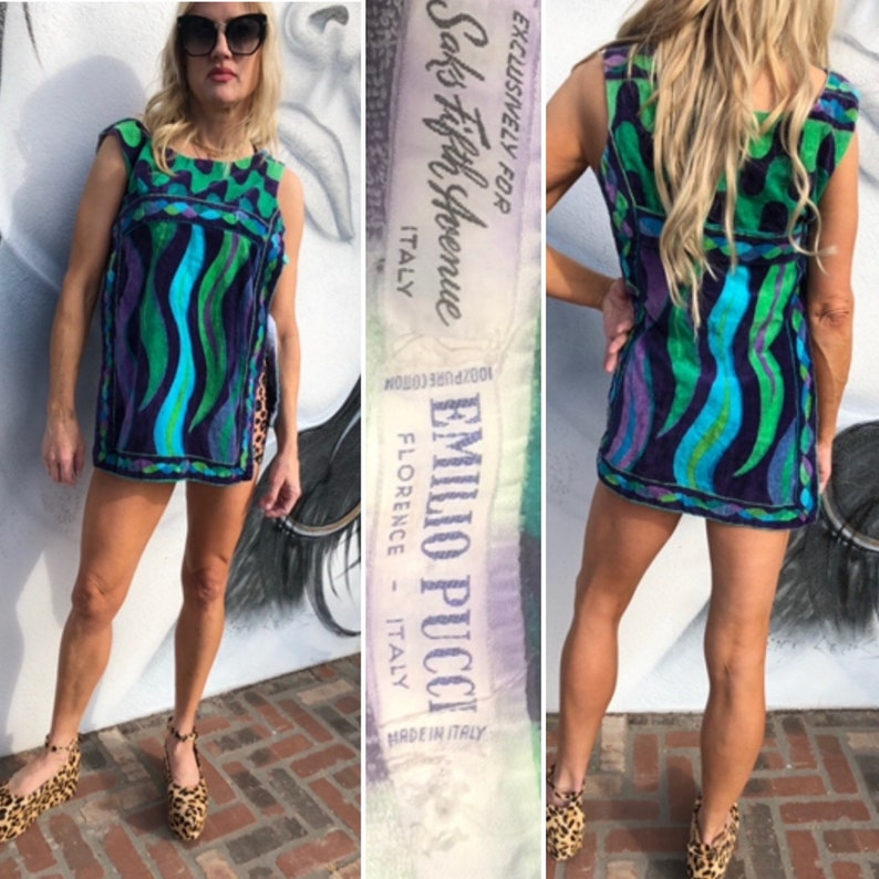 May include: A blue, green, and purple patterned mini dress with a sleeveless design. The dress has a label that reads "Emilio Pucci, Florence - Italy, Exclusively for Saks Fifth Avenue, Made in Italy".