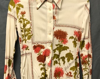 Puede incluir: Una camisa de manga larga con botones, fondo blanco y estampado floral. Las flores son rojas, naranjas y verdes. La camisa tiene cuello y cierre de botones. El texto "Chrysantheme" está impreso en la camisa.