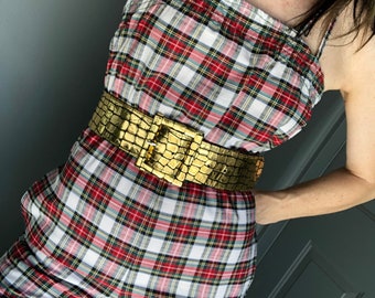 May include: A red, white, and green plaid jumpsuit with a gold, textured belt. The belt has a large, gold buckle.