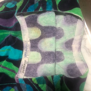 May include: A green, blue, and purple patterned towel with a white label that reads "Emilio Pucci, Made in Italy,  Sole Agent for America, Saks Fifth Avenue".