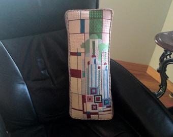 May include: A rectangular pillow with a geometric pattern in shades of pink, green, blue, and red. The pattern is reminiscent of a cityscape.