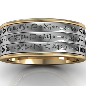 May include: A gold and silver band with a spinning design. The band has multiple rings with engraved text in a circular pattern.