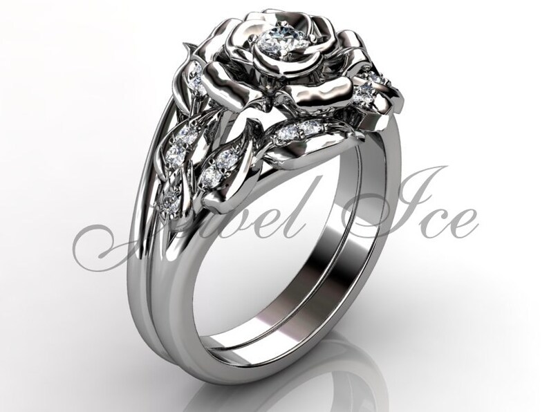 Puede incluir: Un anillo de compromiso de oro blanco en forma de rosa con un diamante central y diamantes m&aacute;s peque&ntilde;os en la banda y los p&eacute;talos de la rosa.