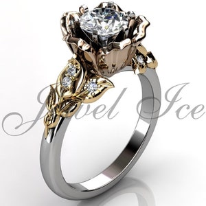 May include: A rose-shaped engagement ring featuring a large, round, clear diamond in the centre. The ring is crafted from white gold and yellow gold, and boasts delicate leaves and smaller diamonds on the band.