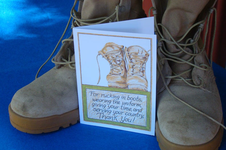 Op de afbeelding: Een bedankkaart met een aquarel illustratie van gevechtslaarzen. De tekst luidt: "Voor het rucking in laarzen, het dragen van het uniform, het geven van je tijd en het dienen van je land, bedankt!" De kaart staat voor een paar militaire laarzen.