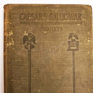 May include: A green book with the title "Caesar's Gallic War" printed on the front cover. The book has two illustrations of eagles on the front cover.