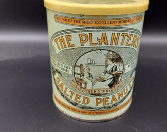 May include: A vintage tin can of Planters Salted Peanuts. The can is yellow with a green and white label featuring a woman and child in a kitchen setting. The label reads "The Planters Mother's Brand Salted Peanuts".