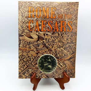 May include: A vintage book cover with the title "Rome of the Caesars" in orange text. The cover features an aerial view of the ancient city of Rome with a Roman coin in the foreground.
