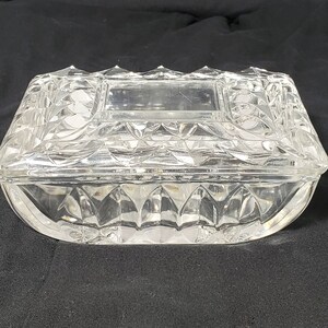 May include: A clear glass trinket box with a cut glass design. The box has a hinged lid and a clear glass interior.