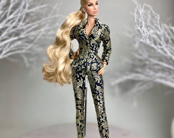May include: A fashion doll wearing a black and gold patterned pantsuit with a high ponytail. The doll is standing on a white display stand with the text "NU.FACE" printed on it.