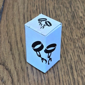 May include: White box with black and white illustrations of two handcuffs. The handcuffs are in a closed position.