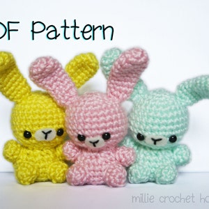 Könnte beinhalten: Drei kleine gehäkelte Stofftiere in Gelb, Rosa und Mintgrün, jeweils mit langen Ohren, schwarzen Perlenaugen und einer gestickten Nase. Der Text PDF Pattern steht oben und millie crochet house steht unten im Bild.