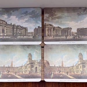 May include: Set of four rectangular coasters featuring historical architectural illustrations. Each coaster displays a different Dublin landmark: Trinity College, The Parliament House, and Great Court Yard, Dublin Castle. The coasters have a vintage aesthetic.