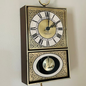 May include: A vintage Westclox Electric wall clock with a gold-tone frame and ornate details. The clock face has Roman numerals and a black and white pendulum.