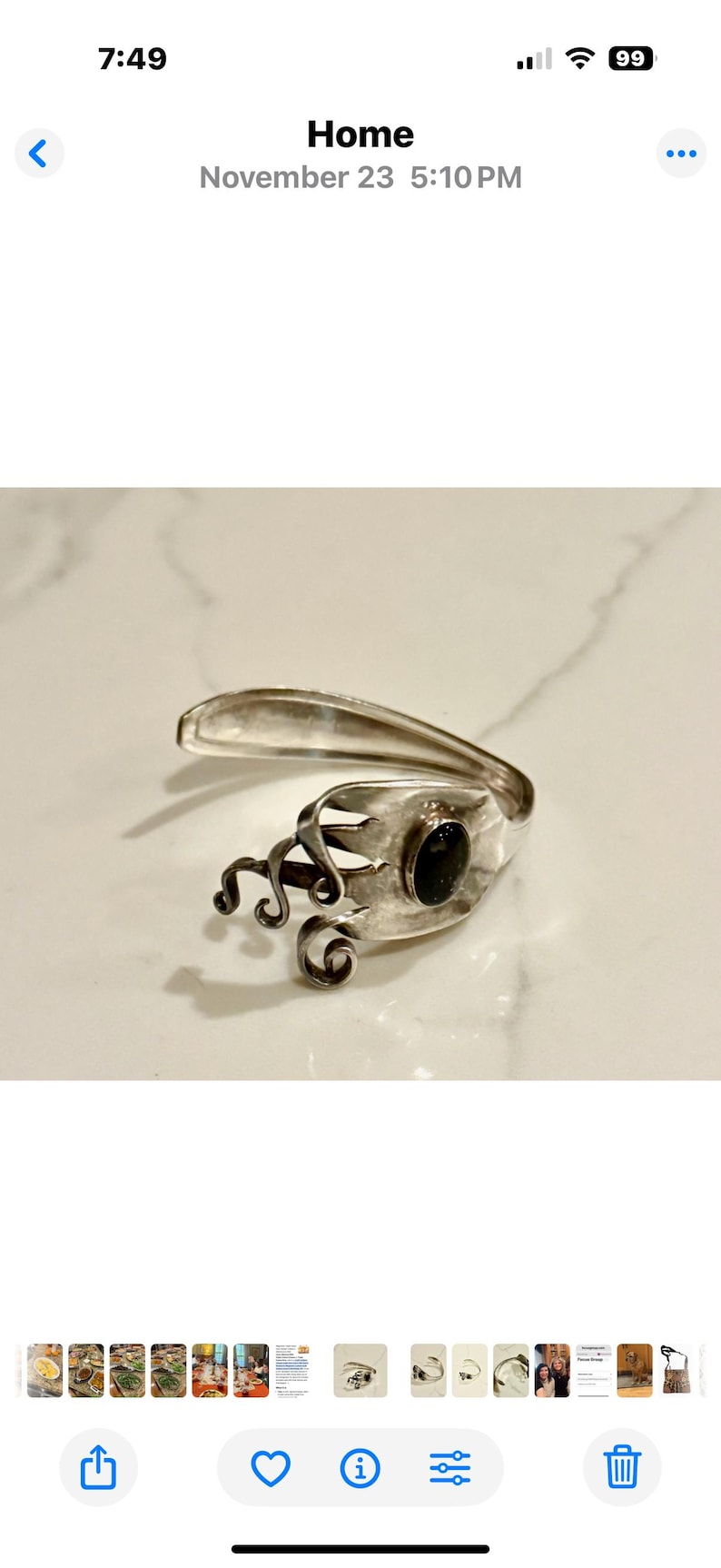 May include: A silver-toned bracelet crafted from a repurposed fork. The design features a dark, oval-shaped stone set within the fork's tines, with decorative swirls. The bracelet is displayed on a white marble surface.