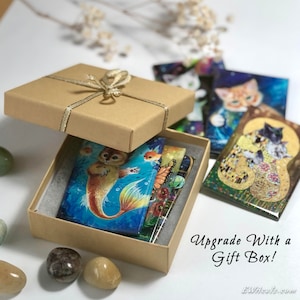 May include: A set of colourful cat-themed magnets in a brown gift box with a gold ribbon. The magnets feature various cat illustrations, including a mermaid cat, a cat with fish, and a cat with butterflies. The box is tied with a gold ribbon and has the text "Upgrade With a Gift Box!" printed on the front.