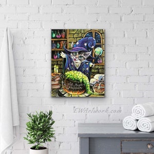 May include: A gray and white cat wearing a blue and purple wizard hat with stars and a pointed hat. The cat is holding a wand and is standing in front of a cauldron with green liquid. The cauldron is on a table with books, a chest, and a candle. The text "Let Magic Happen" is written on the cauldron.