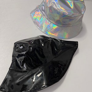 K&ouml;nnte beinhalten: Zwei Bucket-Hats, einer silberfarben mit holografischem Finish und einer schwarz mit gl&auml;nzendem Finish.