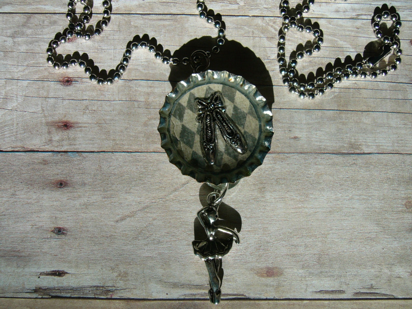the magic of dance, a bottle cap pendant with a pair of ballet shoes on a harlequin patterned background and a 3d ballet dancer