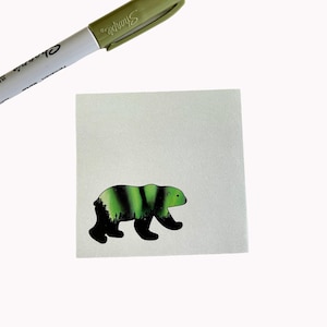 Puede incluir: Una silueta de oso verde y negro con una escena de bosque en su interior. El oso camina hacia la derecha.