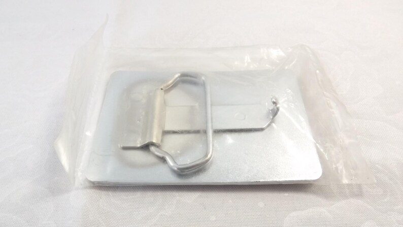 May include: A silver metal belt buckle with a rectangular shape and a simple design. The buckle has a smooth, polished finish and a single, hinged closure.