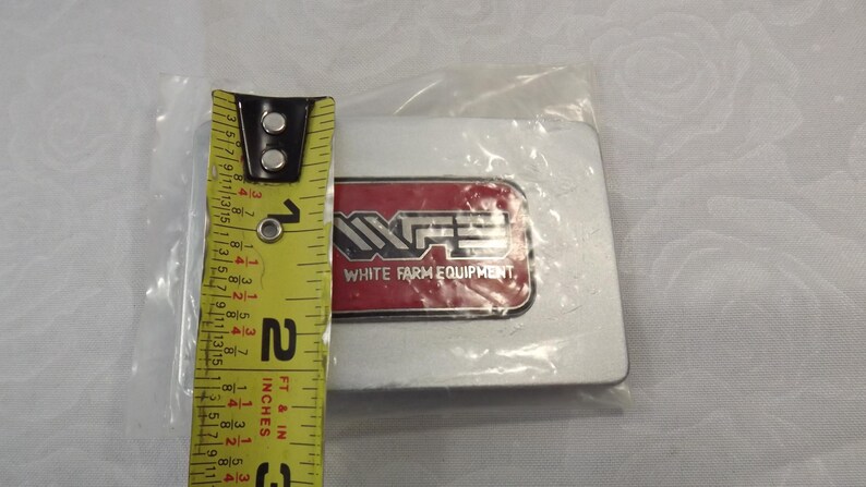 May include: A silver metal emblem with a red and white logo that says "White Farm Equipment".