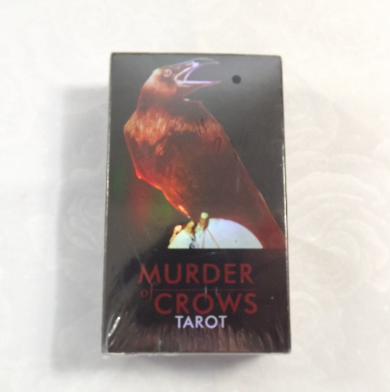 May include: A black box with a red crow on the front. The box says "Murder of Crows Tarot" on the front.