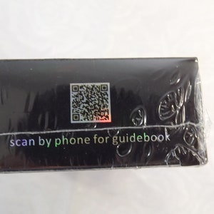 May include: Black box with a QR code and the text "scan by phone for guidebook".