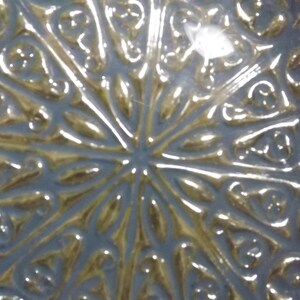 Puede incluir: Primer plano de un plato decorativo con acabado met&aacute;lico plateado y dorado. El plato tiene un dise&ntilde;o intrincado en relieve que se asemeja a una flor o una estrella.