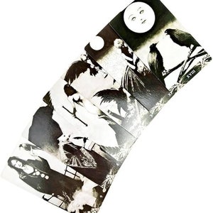May include: A set of black and white tarot cards with illustrations of people and ravens. The cards are arranged in a fan shape, with the top card showing a full moon and the number XVIII.