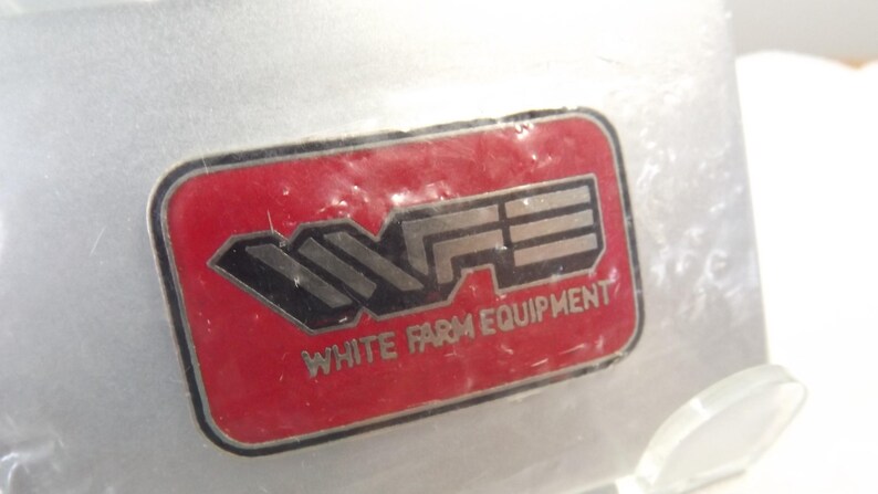 May include: A red and silver logo with the letters "WFE" and the text "White Farm Equipment" underneath.