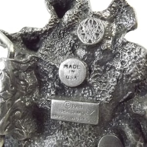 K&ouml;nnte beinhalten: Eine silberne G&uuml;rtelschnalle mit einem detaillierten Drachenmotiv. Die Schnalle ist mit "Made in USA" und "C 1981 BERGAMO BRASS WORKS" gekennzeichnet.