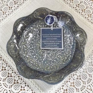 Puede incluir: Dos platos de vidrio azul con un intrincado dise&ntilde;o en relieve. Los platos est&aacute;n decorados a mano y se recomienda lavarlos a mano. El texto de la etiqueta dice: "Vidrio decorado a mano Lavado a mano recomendado Hecho en Turqu&iacute;a"