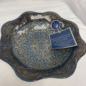 Puede incluir: Un cuenco de vidrio decorativo azul y dorado con un dise&ntilde;o intrincado. El cuenco est&aacute; hecho a mano y se recomienda lavarlo a mano. La etiqueta dice "Genuine Silver" y "Hecho en Turqu&iacute;a".