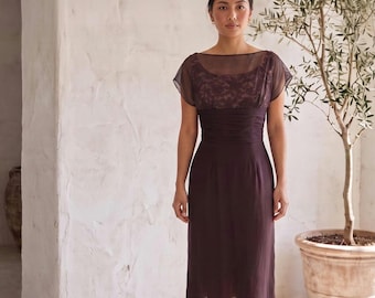 May include: A dark brown midi dress featuring a sheer overlay with a delicate lace pattern on the bodice, short cap sleeves, a wide ruched waistband, and a straight skirt that falls below the knees with a semi-sheer hemline and a solid lining.