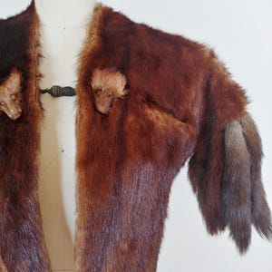 May include: A vintage brown fur jacket with a dark clasp closure. The jacket features a rich, reddish-brown color with varying shades and textures. The sleeves end in a darker, fur trim.