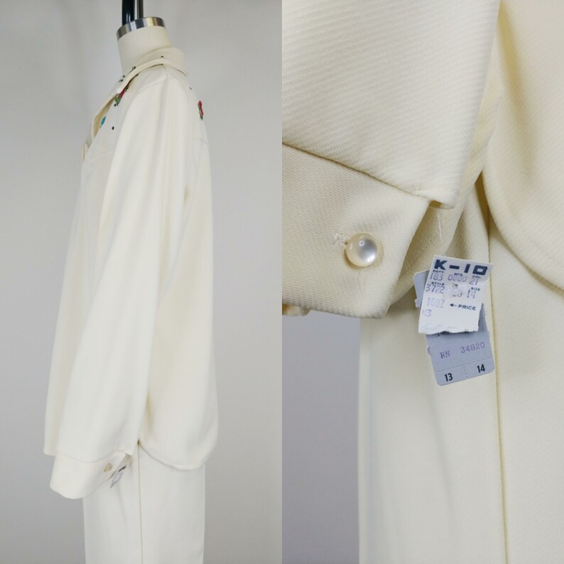 Peut inclure: Un ensemble chemise et pantalon blanc &agrave; manches longues avec un bouton en perle et des fleurs brod&eacute;es. La chemise a un col et le pantalon a une jambe droite. L'&eacute;tiquette indique "K-10 103 000 37 372 13 17 1002" et "RN 34030 13 14".