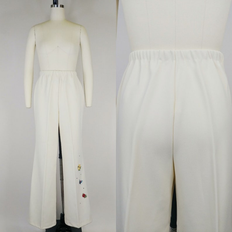Peut inclure: Pantalon blanc &agrave; jambes larges avec une l&eacute;g&egrave;re &eacute;vas&eacute;e en bas. Le pantalon a un design simple et est d&eacute;cor&eacute; de petites fleurs brod&eacute;es color&eacute;es sur la jambe droite.