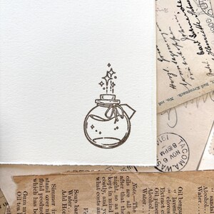 May include: A hand-drawn illustration of a glass bottle with a cork stopper and a ribbon tied around the neck. Stars are coming out of the bottle, suggesting magic or a potion.