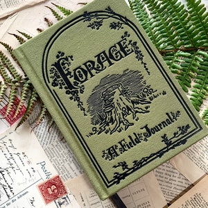 Può includere: Un diario verde con la parola "FORAGE" in lettere nere sulla copertina. Il diario ha anche un'illustrazione nera di un albero e le parole "Field Journal" sulla copertina.
