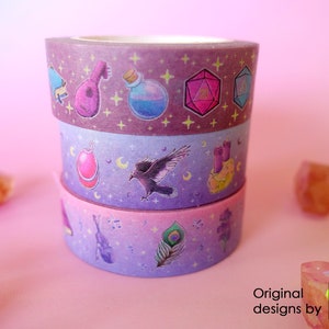 Washi tapes with a pattern of Dungeons and Dragons elements on a purple background. Three rolls are piled, one of each pattern.