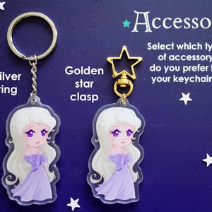May include: Two keychains with a cartoon illustration of a woman in a purple dress. One keychain has a silver ring, the other a golden star clasp. The text reads "Accessory" and "Select which type of accessory do you prefer for your keychains."