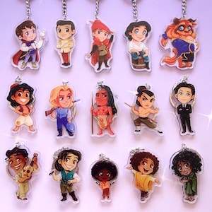May include: A collection of cartoon character keychains. Each keychain features a different character with a unique design and color scheme. The keychains are attached to silver-colored metal chains. The characters include a prince, a beast, and other animated figures.