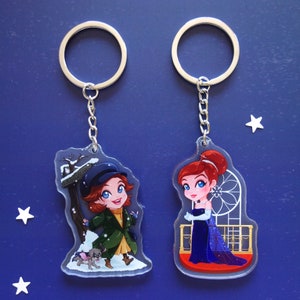 Clear acrylic keychains 6cm with silver ring of Anastasia. In the left, she's in the snow with Pooka and a signal which says St. Petersburg. In the right, she wears a bluedress from the opera in Paris scene.