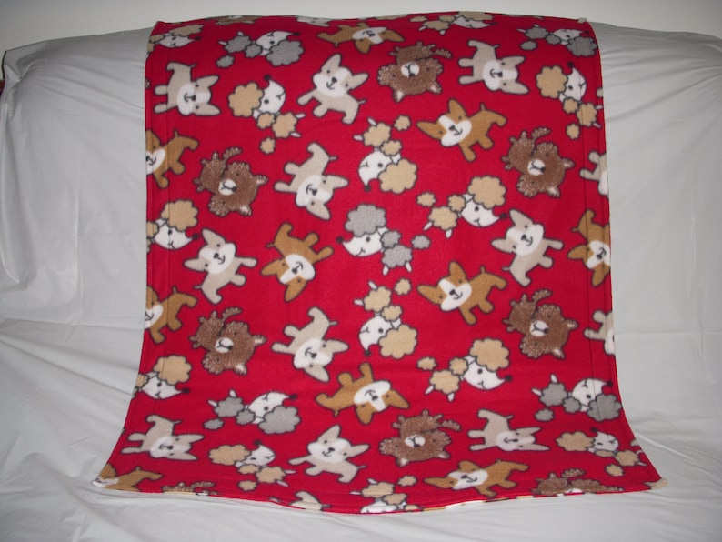 cute little puppies on red print fleece with the same pattern on the reverse side. Doggy Blanket