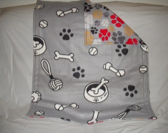 Doggy Blanket - dog toys, bones and black paws on gray fleece with large red, yellow, black, gray and white paws on gray on the reverse side